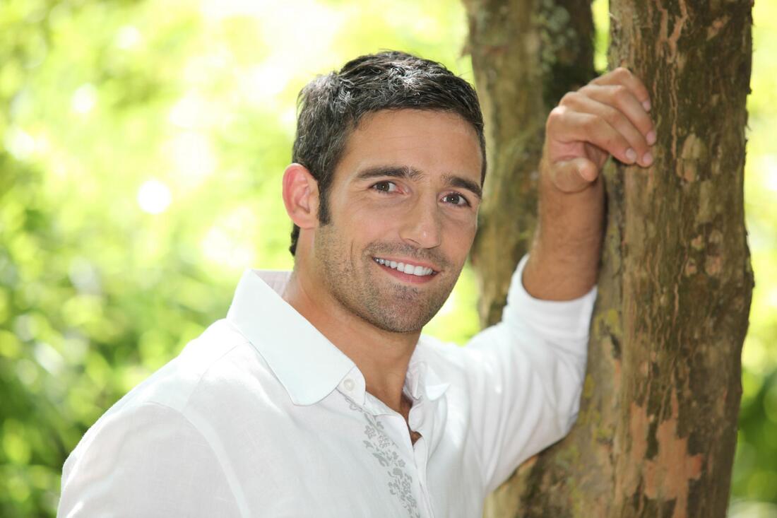 man smiling leaning on the tree